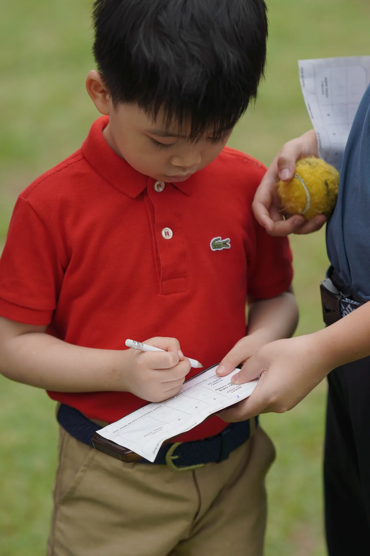 Scorecard là gì? Cách ghi điểm golf đơn giản - Golfer nhí ghi điểm và ký scorecard